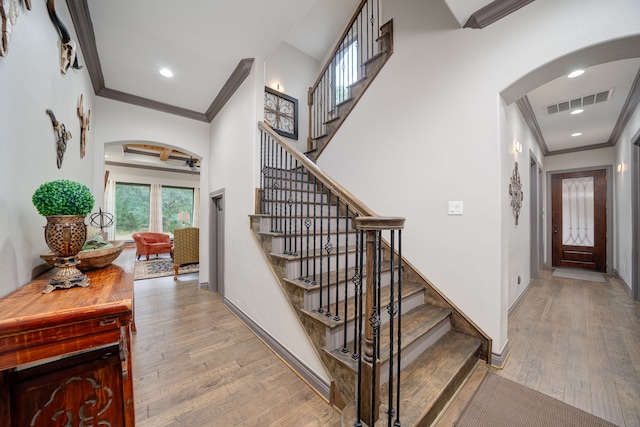 stairs with hardwood / wood-style flooring and crown molding