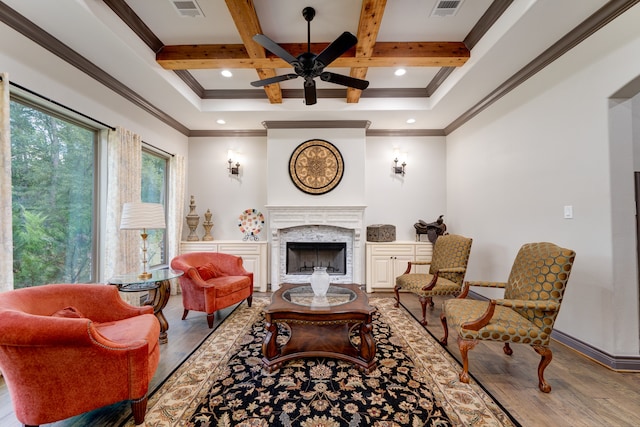 living room featuring a fireplace, crown molding, wood-type flooring, beam ceiling, and ceiling fan