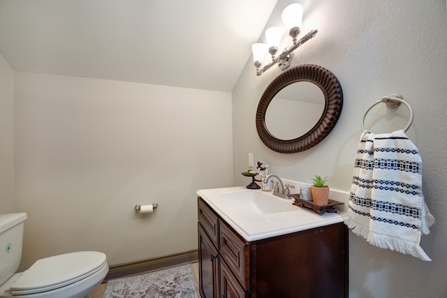 bathroom with vanity, toilet, and vaulted ceiling