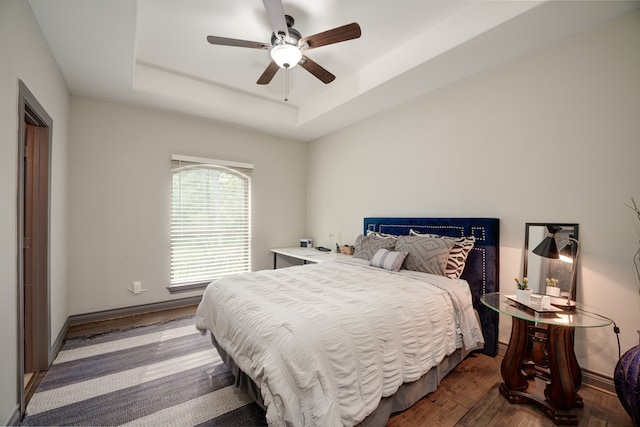 bedroom featuring a raised ceiling, hardwood / wood-style floors, and ceiling fan