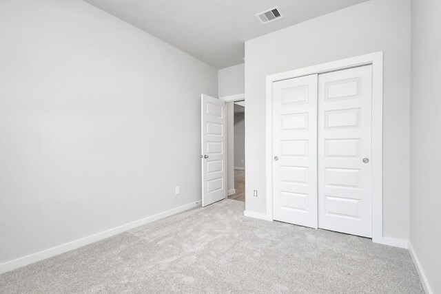 unfurnished bedroom featuring light carpet and a closet