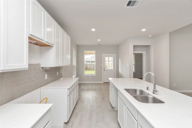 kitchen featuring white cabinets, backsplash, light hardwood / wood-style floors, and sink