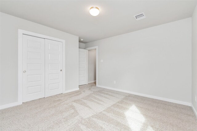 unfurnished bedroom with light carpet and a closet