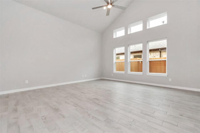 empty room featuring light hardwood / wood-style floors, ceiling fan, and high vaulted ceiling