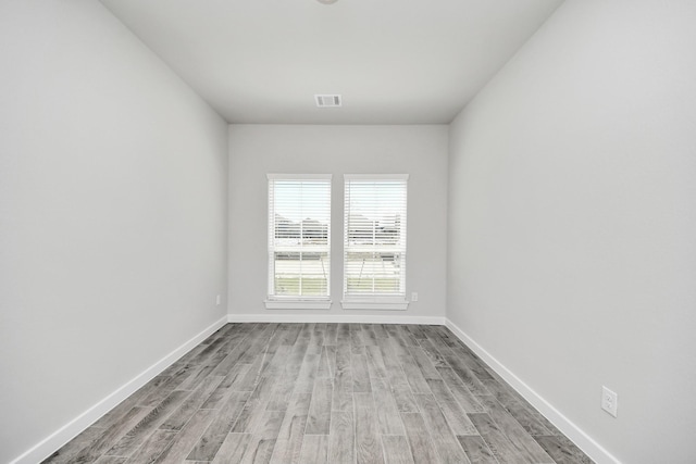 spare room with visible vents, baseboards, and wood finished floors