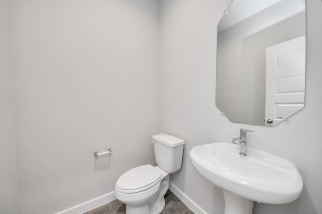 bathroom with a sink, baseboards, and toilet