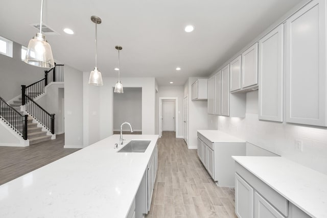 kitchen featuring a sink, light wood-type flooring, tasteful backsplash, and recessed lighting