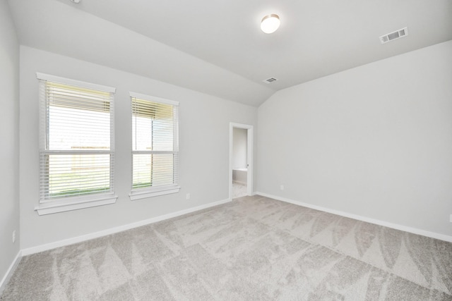 carpeted spare room featuring visible vents, baseboards, and lofted ceiling