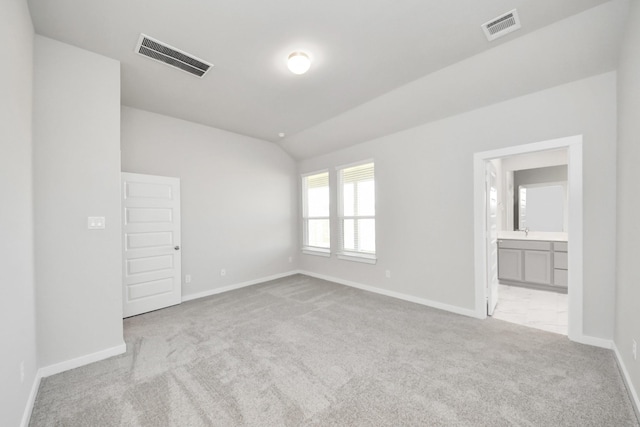 carpeted empty room featuring visible vents, a sink, baseboards, and vaulted ceiling