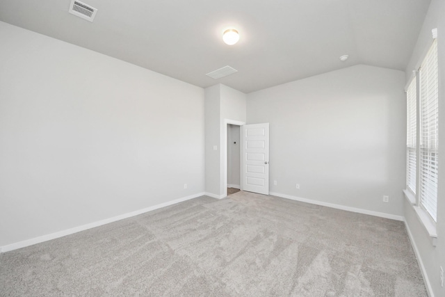 carpeted spare room with visible vents, baseboards, and lofted ceiling