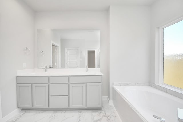 full bathroom with a bath, marble finish floor, baseboards, and double vanity