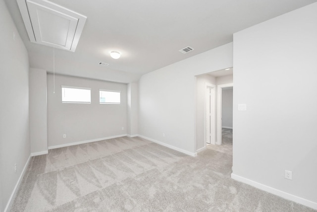 unfurnished room featuring light carpet, visible vents, attic access, and baseboards