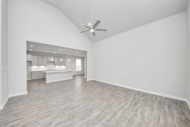 unfurnished living room with baseboards, light wood-type flooring, and a ceiling fan