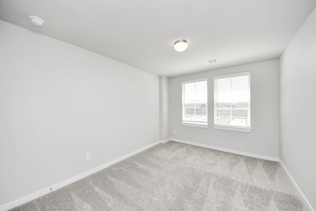 unfurnished room with visible vents, light colored carpet, and baseboards