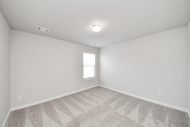 carpeted spare room featuring baseboards and visible vents