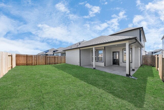 back of property featuring a patio, a lawn, a fenced backyard, and roof with shingles