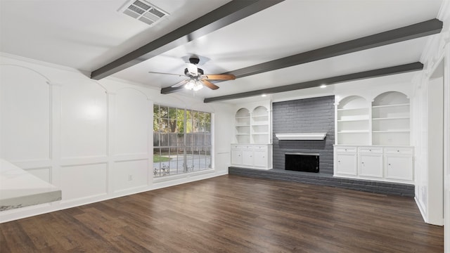 unfurnished living room featuring dark wood-type flooring, built in shelves, beam ceiling, a fireplace, and ceiling fan