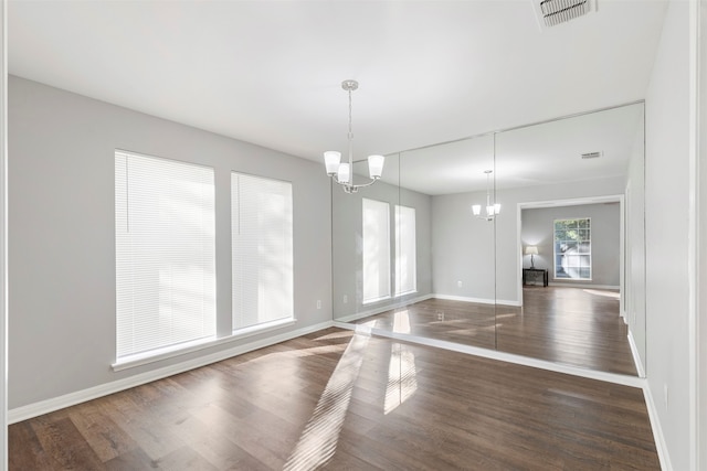 unfurnished dining area with a notable chandelier and dark hardwood / wood-style floors