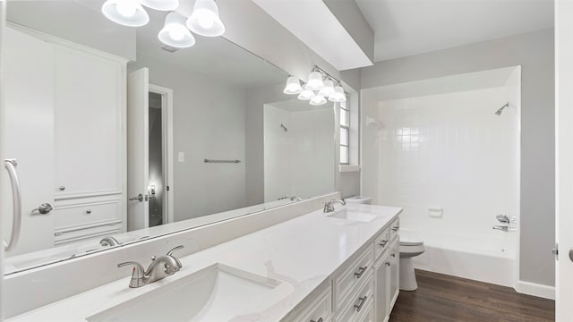 full bathroom with wood-type flooring, tiled shower / bath combo, vanity, and toilet