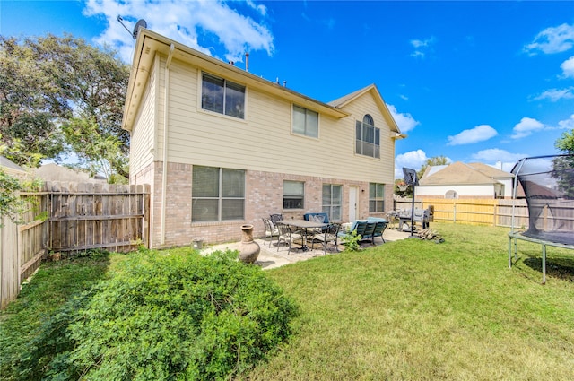 rear view of property featuring a patio, a trampoline, and a lawn