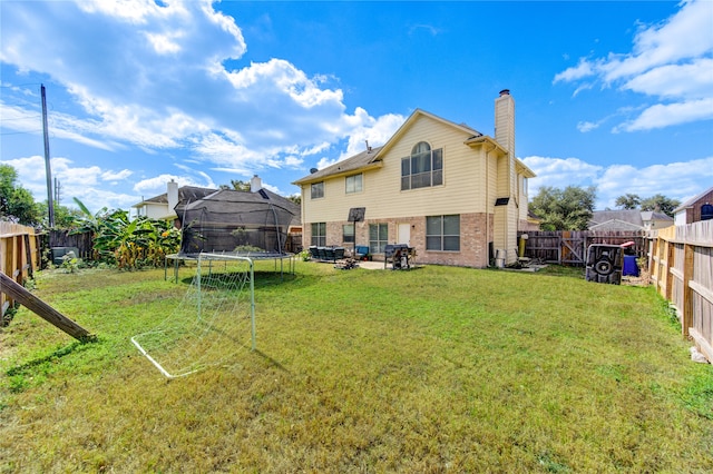 rear view of property with a patio area, a trampoline, and a lawn