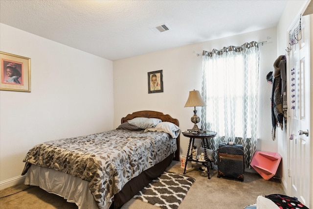 carpeted bedroom featuring baseboards, visible vents, and a textured ceiling