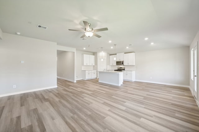 unfurnished living room featuring ceiling fan and light wood-type flooring