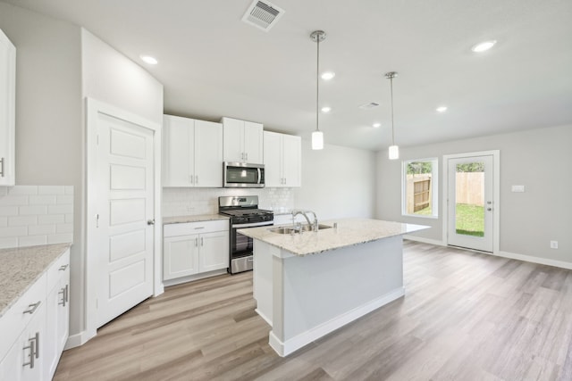 kitchen featuring hanging light fixtures, stainless steel appliances, light stone counters, white cabinets, and light wood-type flooring