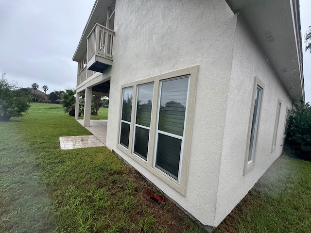 view of property exterior featuring a balcony and a yard