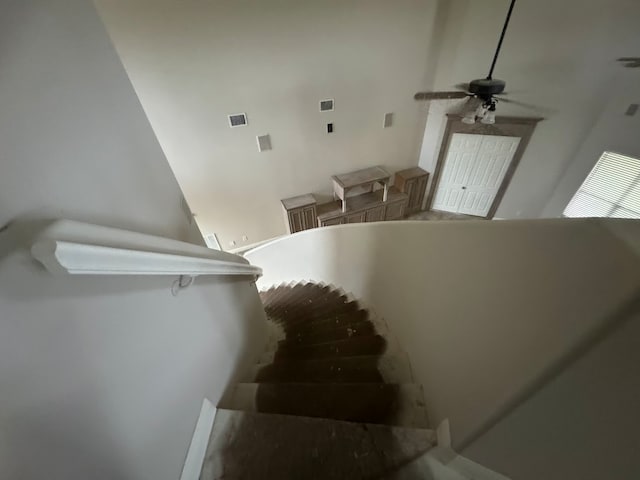 stairs featuring a towering ceiling and ceiling fan