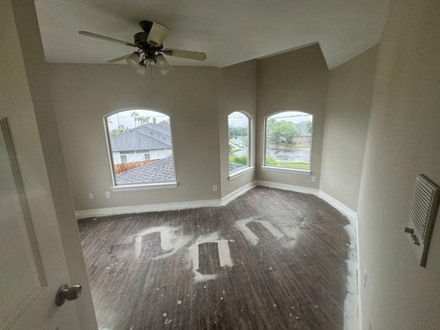 unfurnished room with dark wood-type flooring, ceiling fan, and a wealth of natural light