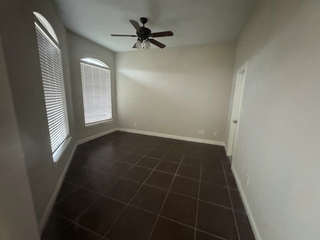 unfurnished room featuring ceiling fan and dark tile patterned floors