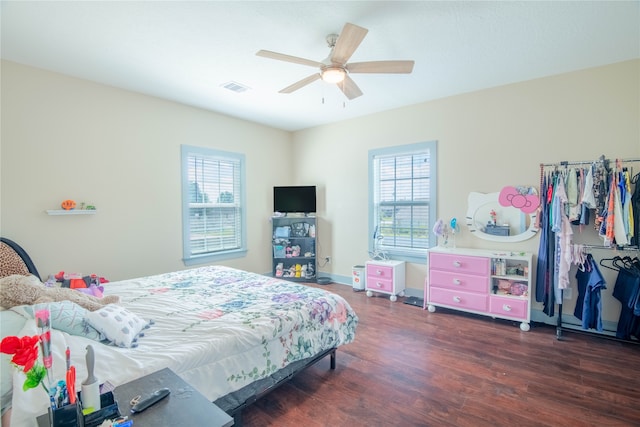 bedroom with ceiling fan, dark wood-type flooring, and multiple windows