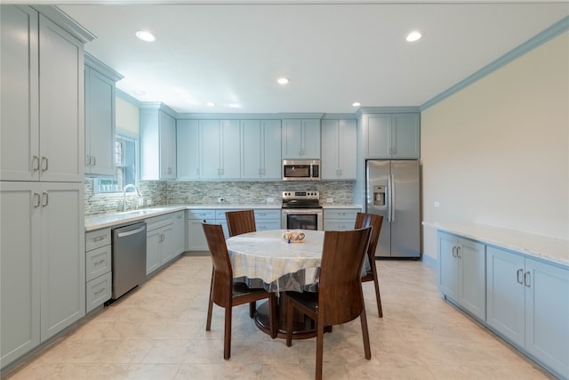 kitchen with sink, appliances with stainless steel finishes, light stone countertops, crown molding, and decorative backsplash