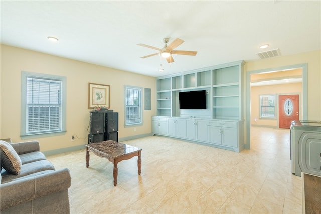 living room featuring ceiling fan, plenty of natural light, and built in features