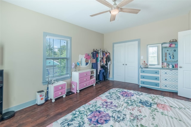 bedroom featuring multiple windows, dark hardwood / wood-style flooring, ceiling fan, and a closet