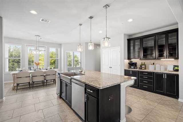 kitchen with backsplash, a kitchen island with sink, dishwasher, pendant lighting, and sink