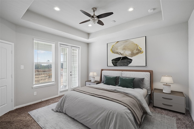 carpeted bedroom with a raised ceiling, multiple windows, access to outside, and ceiling fan