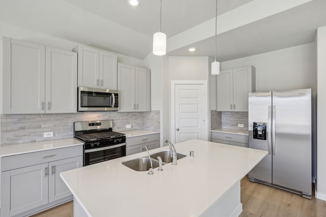 kitchen featuring stainless steel appliances, sink, a center island with sink, and decorative light fixtures