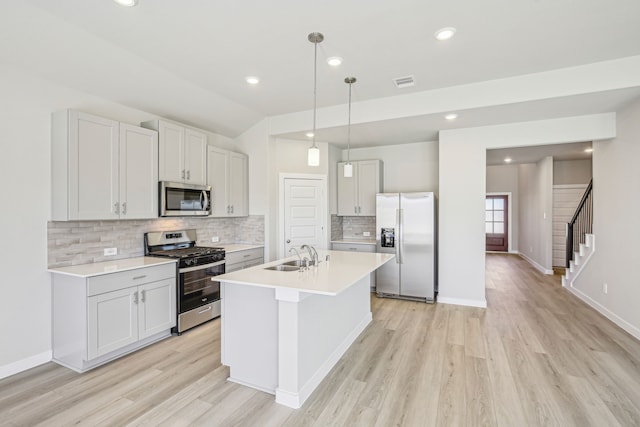 kitchen featuring pendant lighting, sink, stainless steel appliances, and light wood-type flooring