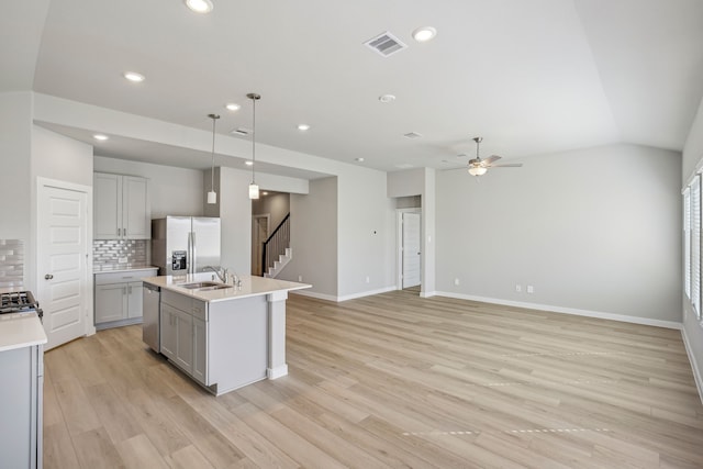 kitchen featuring gray cabinets, appliances with stainless steel finishes, pendant lighting, sink, and a kitchen island with sink