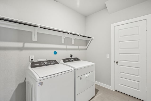 laundry area with washing machine and clothes dryer and light tile patterned flooring