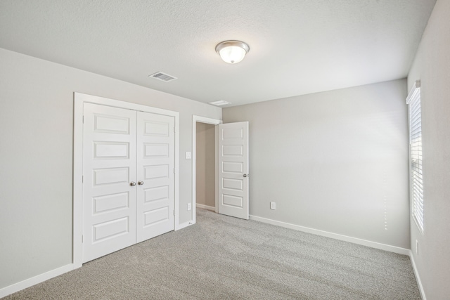 unfurnished bedroom featuring a closet, light carpet, and a textured ceiling