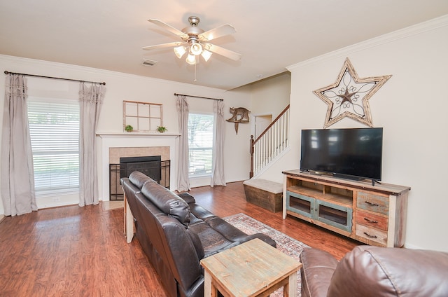 living room with ceiling fan, ornamental molding, dark hardwood / wood-style flooring, and a tile fireplace