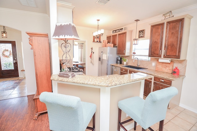 kitchen with appliances with stainless steel finishes, a kitchen breakfast bar, crown molding, light hardwood / wood-style flooring, and decorative light fixtures