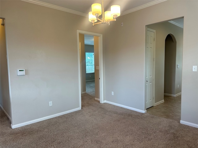 carpeted spare room featuring an inviting chandelier and crown molding