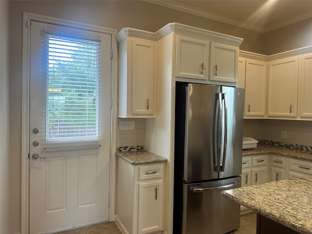 kitchen featuring decorative backsplash, white cabinets, light stone countertops, and stainless steel refrigerator