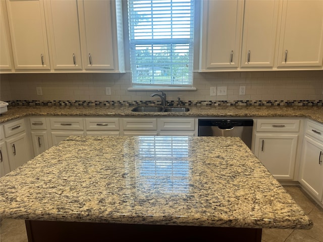 kitchen featuring light stone counters, sink, white cabinetry, a kitchen island, and stainless steel dishwasher