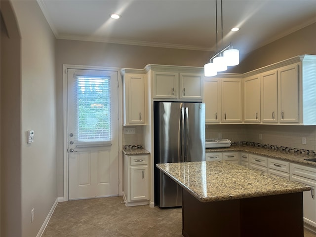 kitchen with light stone counters, stainless steel fridge, tasteful backsplash, white cabinetry, and a center island