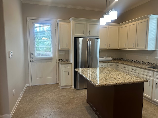 kitchen with white cabinetry, stainless steel refrigerator, backsplash, a kitchen island, and ornamental molding